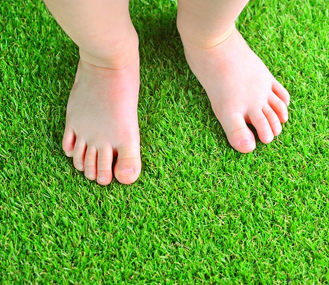 Artificial grass, like Astro Turf, installed in Boca Raton, with young child's feet standing