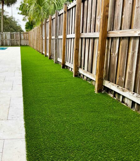 Synthetic grass in a Jupiter, FL backyard by a fence